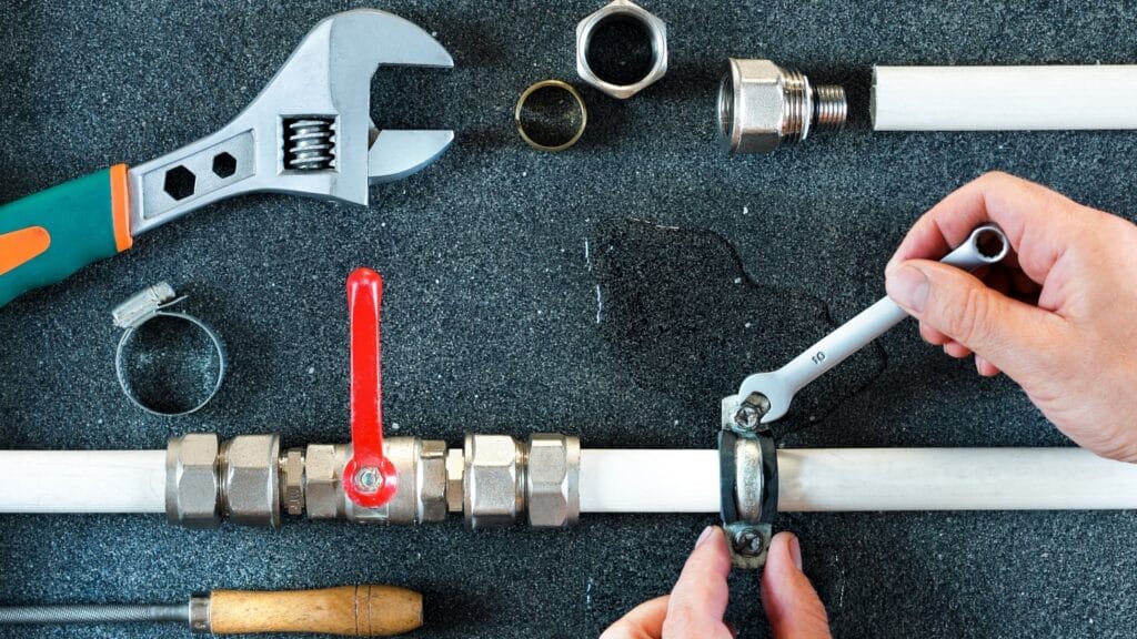 Plumber repairing a pipe valve with an adjustable wrench in Golden