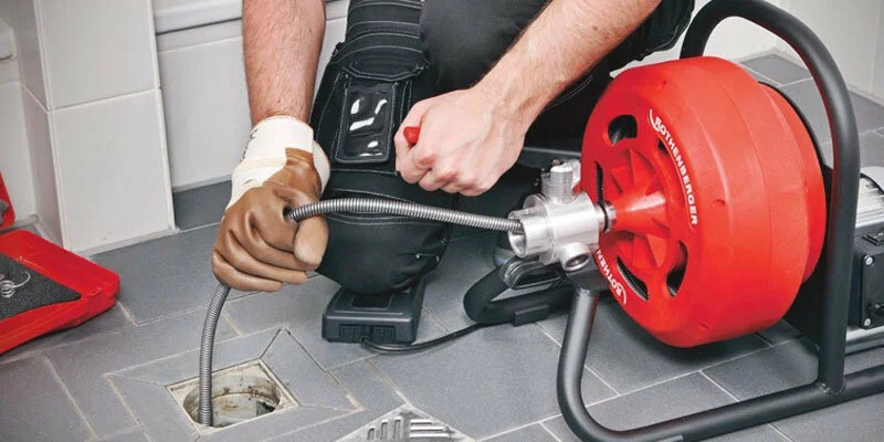 Plumber using a drain-cleaning machine in Golden